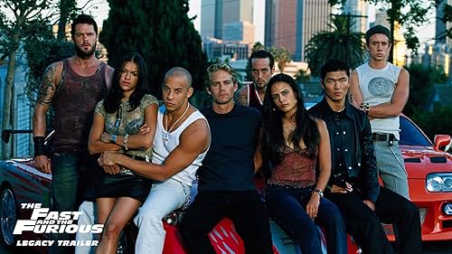 C'est une photo promotionnelle du casting original du film "The Fast and the Furious" (2001), posant devant la célèbre Toyota Supra orange. Les acteurs présents sont : Vin Diesel (Dominic Toretto) Paul Walker (Brian O'Conner) Michelle Rodriguez (Letty Ortiz) Jordana Brewster (Mia Toretto) Ainsi que Matt Schulze, Chad Lindberg